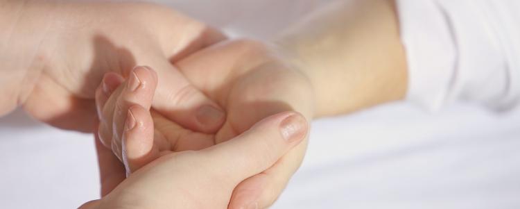 En vuxen hand som rör vid och masserar ett barns hand